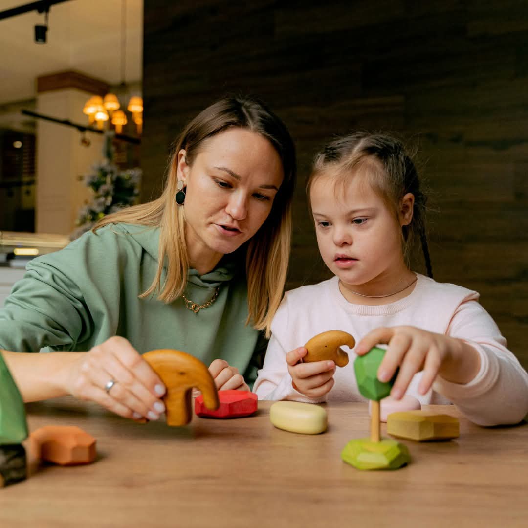 A Crescent Care worker and a young child playing together with wooden toys