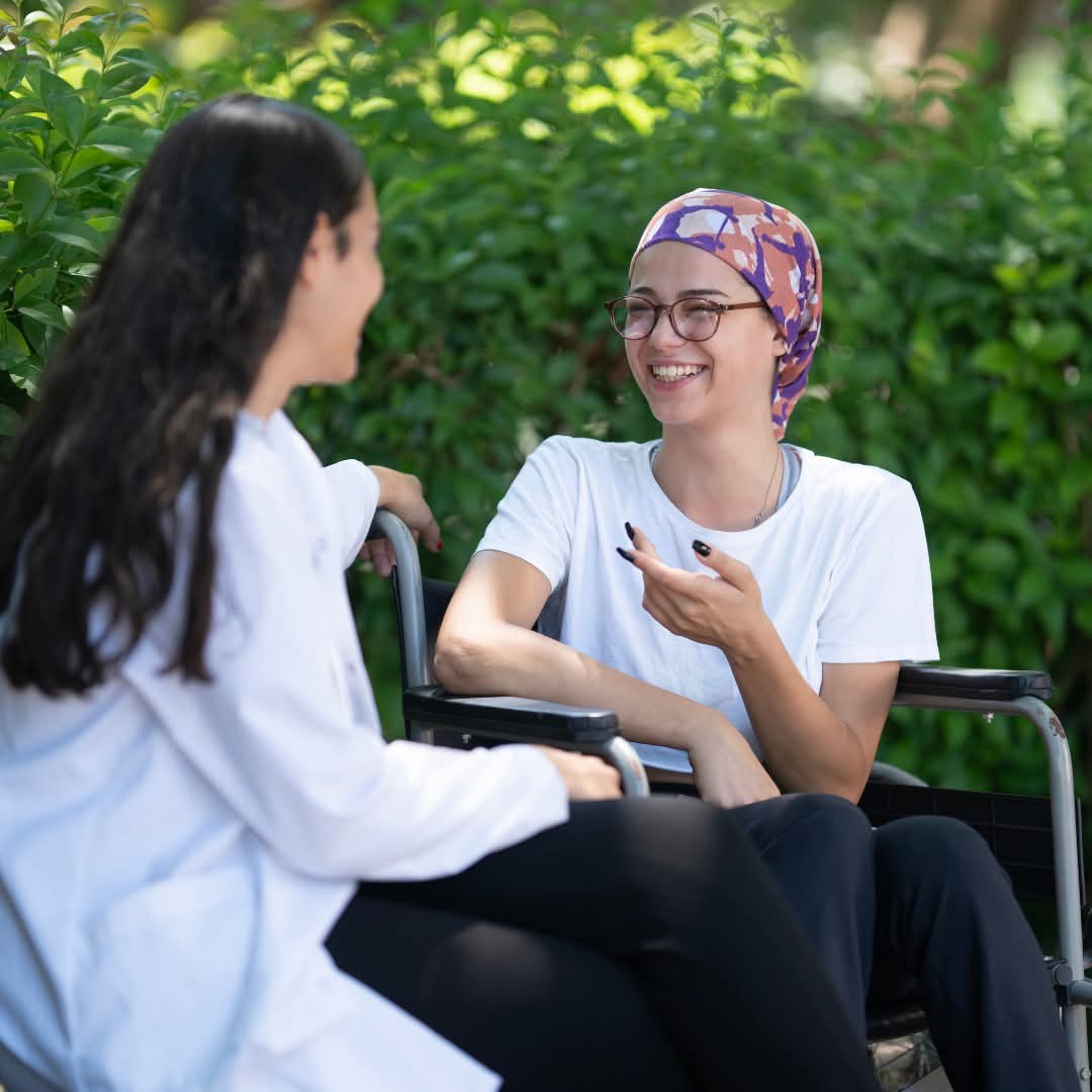 A Crescent Care participant in a wheelchair having a warm conversation with her support worker outdoors